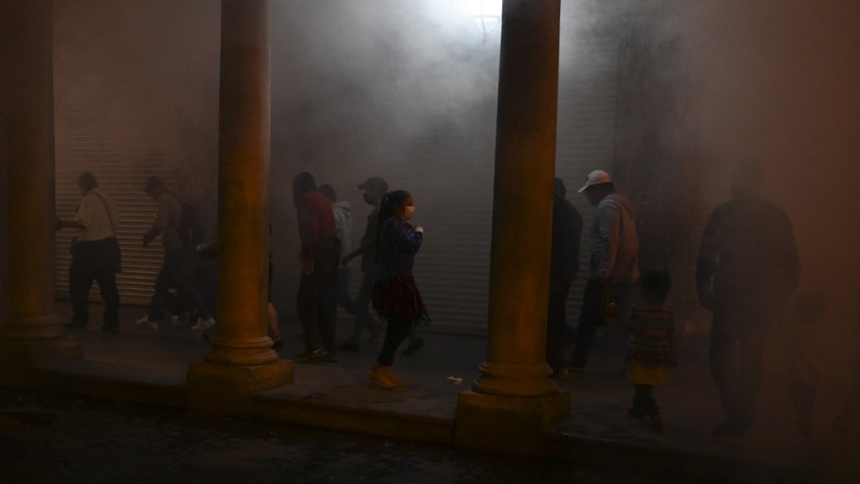 Personas pasan por una nube de desinfectante en Ciudad de Guatemala